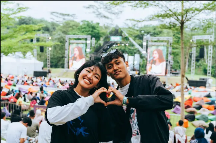 Sepasang pengunjung membentuk hati dengan tangan di depan area beanbag