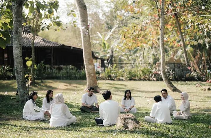 Peserta berbaju putih duduk melingkar di atas rumput