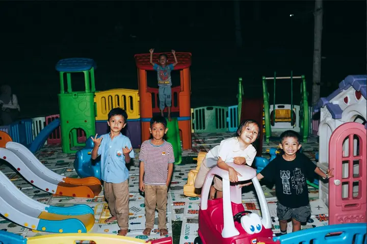 Anak-anak bermain di area bermain dengan perosotan warna-warni
